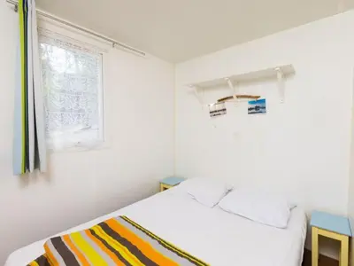 a white bedroom with a bed and a window at Mobil-home avec Terrasse à Lézignan-Corbières, 6 personnes - API-1-52-736 in Lézignan-Corbières