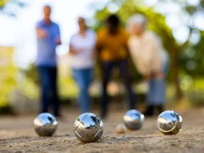 four silver balls sitting on the ground with people in the background at Mobil home spacieux avec terrasse pour 8 personnes - API-1-52-793 in Lézignan-Corbières