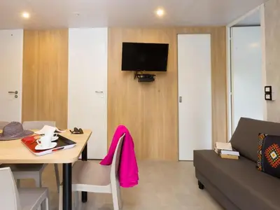 a living room with a table and a couch at Mobil home spacieux avec terrasse pour 8 personnes - API-1-52-793 in Lézignan-Corbières