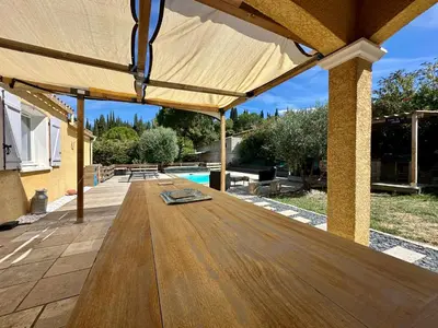 a wooden table on a patio with a pool at Villa FURGY - Climatisation et parking in Carcassonne