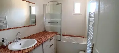 a bathroom with a sink and a shower and a tub at Villa Standing Piscine Chauffée in Gruissan