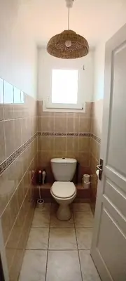 a bathroom with a toilet and a window at Villa Standing Piscine Chauffée in Gruissan
