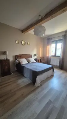 a bedroom with a large bed and a wooden floor at Charmant maison de village in Rieux-Minervois