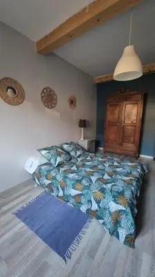 a bedroom with a bed with a blue comforter at Charmant maison de village in Rieux-Minervois