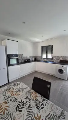 a large kitchen with white cabinets and a microwave at Charmant maison de village in Rieux-Minervois