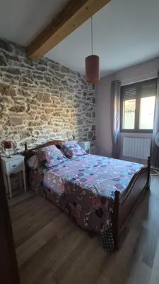 a bedroom with a bed and a stone wall at Charmant maison de village in Rieux-Minervois