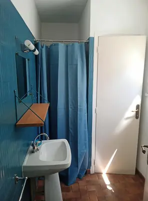 a bathroom with a sink and a blue shower curtain at Les Yeuses in Brousses-et-Villaret