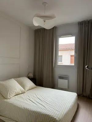 a white bedroom with a bed and a window at Apt T2 moderne & lumineux in Narbonne