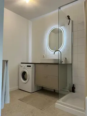a bathroom with a washing machine and a mirror at Apt T2 moderne & lumineux in Narbonne