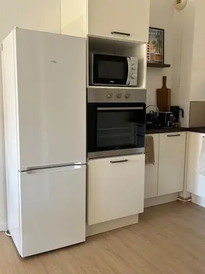 a kitchen with a white refrigerator and a microwave at Apt T2 moderne & lumineux in Narbonne