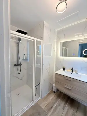 a white bathroom with a shower and a sink at Appartement en centre-ville parking privé in Narbonne
