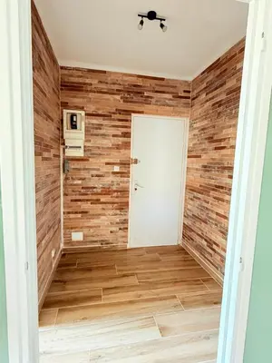 a hallway with a wood accent wall and a white door at Appartement en centre-ville parking privé in Narbonne