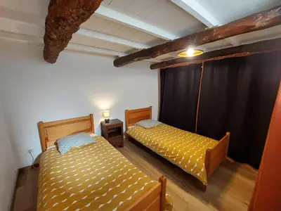 two beds in a room with a black curtain at Au petit hameau Cabrespine in Cabrespine