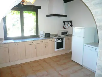 a kitchen with wooden cabinets and a white refrigerator at Cottage in Montbrun-des-Corbières in Montbrun-des-Corbières