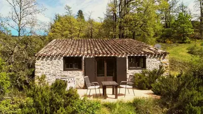 a small stone house with a table and chairs at The Bergerie in Roquetaillade