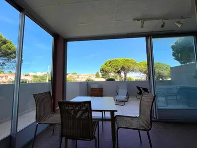 a dining room with a table and chairs on a balcony at Charmant studio grande terrasse in Gruissan