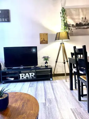 a living room with a flat screen tv and a table at Appartements hyper Centre in Carcassonne