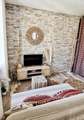a living room with a television and a brick wall at N2 Barbacane-Pieds Cité-Bohème Chic-Clim Mobile in Carcassonne