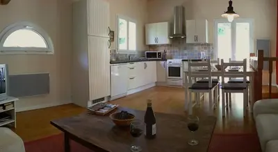 a kitchen and living room with a table with a bottle of wine at The Grange in Roquetaillade