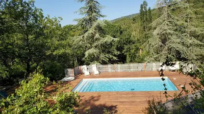 a swimming pool in a yard with a fence and trees at The Grange in Roquetaillade