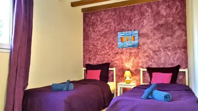 a bedroom with two beds with purple sheets and a window at The Grange in Roquetaillade