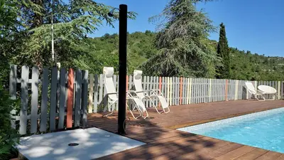 a wooden deck with chairs and a swimming pool at The Grange in Roquetaillade