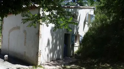 a white building with a dog standing in front of it at The Grange in Roquetaillade