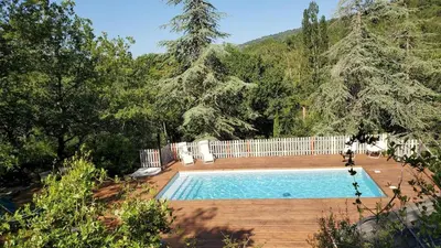 a swimming pool in a yard with a fence and trees at The Studio in Roquetaillade