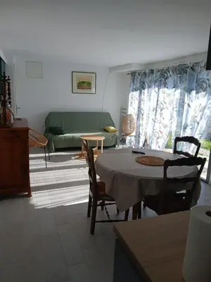 a living room with a table and a green couch at Chez Louise in Arboussols