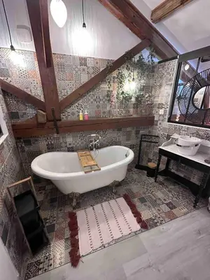 a bathroom with a tub and a tile wall at House Patio Air Conditioning Elegant Decoration in Carcassonne