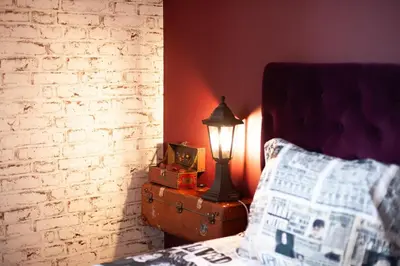 a lamp on a table next to a bed with a newspaper at Qualys Cinema-Parking & View Square in Carcassonne