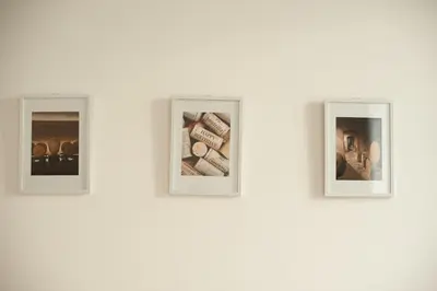 a group of three photographs on a white wall at Qualys Vignoble parking, square view, close to city in Carcassonne
