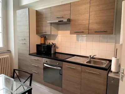 a kitchen with wooden cabinets and a sink at Qualys Vignoble parking, square view, close to city in Carcassonne