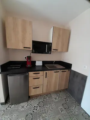 a kitchen with wooden cabinets and a microwave at Chabas Studio in Lagarrigue