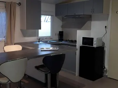 a kitchen with a counter and two bar stools at Mobil-Home avec Jacuzzi pour 4 personnes et Terrasse - API-1-52-465 in Sournia