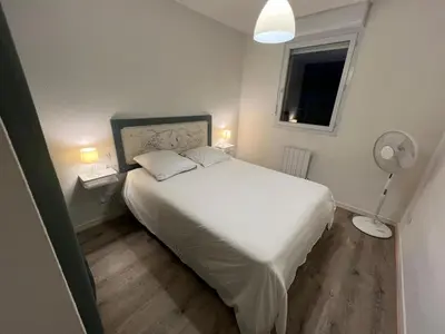a bedroom with a white bed and a fan at Le Parc! T3 climatisé, Parking, Piscine in Carcassonne