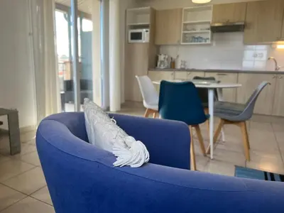 a blue couch in a living room with a kitchen at Le Parc! T3 climatisé, Parking, Piscine in Carcassonne