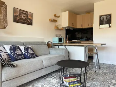 a living room with a couch and a kitchen at Joli Appt Port la Nouvelle in Port-la-Nouvelle