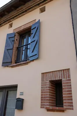a window with blue shutters on a building at La Parenthèse Naillousaine in Nailloux