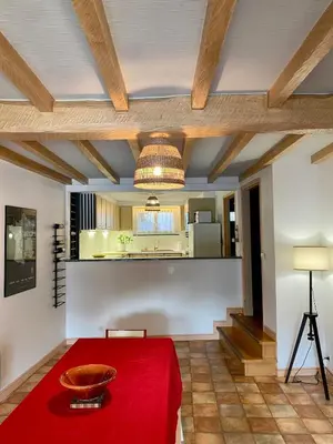 a dining room with a red table and a kitchen at Gîte Massibel au coeur de Brassac in Brassac