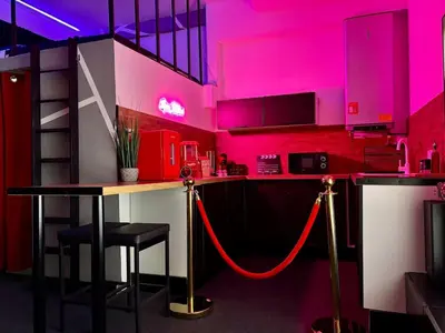 a kitchen with a bar with pink lighting at LOVE IN CINÉ Appartement cinéma balnéo in Pamiers