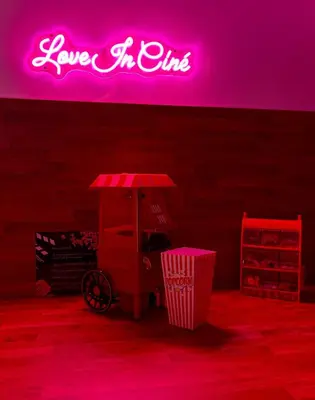 a neon sign on a wall with a food cart at LOVE IN CINÉ Appartement cinéma balnéo in Pamiers