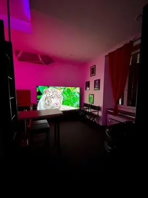 a living room with a large screen tv in a pink room at LOVE IN CINÉ Appartement cinéma balnéo in Pamiers