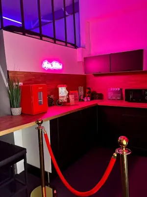 a kitchen with pink lighting and a counter with a red leash at LOVE IN CINÉ Appartement cinéma balnéo in Pamiers