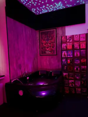 a pink bathroom with a tub and a purple lighting at LOVE IN CINÉ Appartement cinéma balnéo in Pamiers
