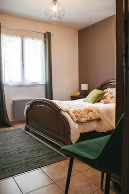 a bedroom with a bed and a chair and a window at L'Eau Vive Villa 6 pers parc 3000m2 à 50 m de la rivière in Fraisse-sur-Agout