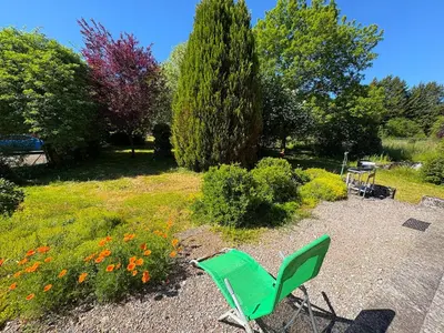 a green chair sitting in the middle of a garden at L'Eau Vive Villa 6 pers parc 3000m2 à 50 m de la rivière in Fraisse-sur-Agout
