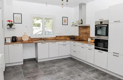 a white kitchen with white cabinets and appliances at L'Escapade Jaune - Jacuzzi, Wi-Fi, tout équipée in Carcassonne