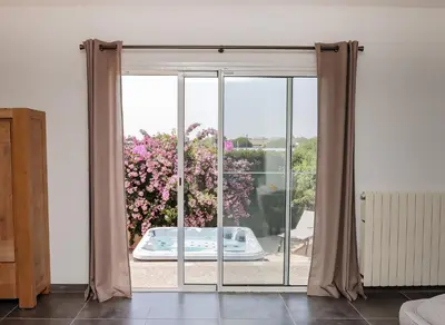 a sliding glass door with a view of a garden at L'Escapade Jaune - Jacuzzi, Wi-Fi, tout équipée in Carcassonne