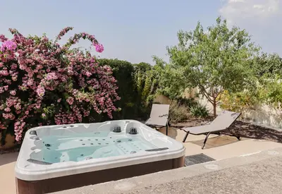 a hot tub on a patio with two chairs and flowers at L'Escapade Jaune - Jacuzzi, Wi-Fi, tout équipée in Carcassonne